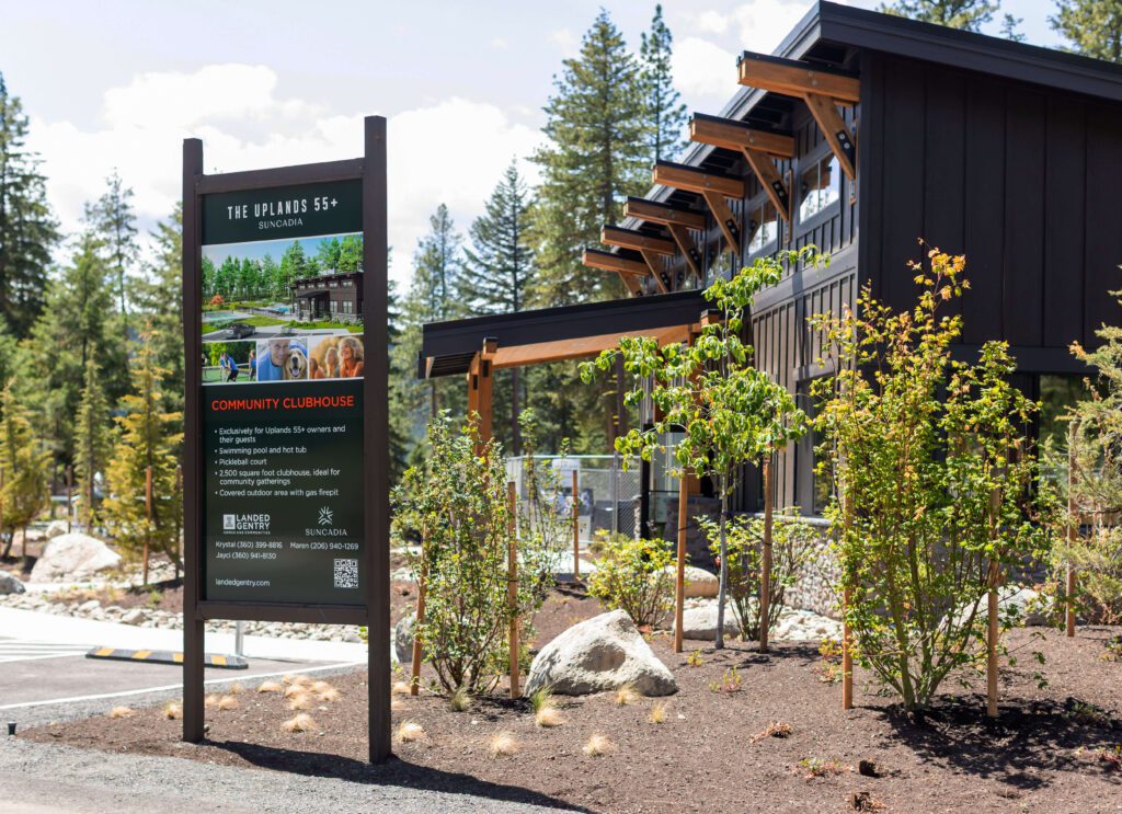 A clubhouse building with a sign in front reading "The Uphill 55+" and "Community Clubhouse," surrounded by trees and landscaping.